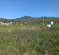Stavebný pozemok v Štitároch 764 m2 s výhľadom na Nitru - Pozemky - bývanie v Štitároch, zelená krajina s výhľadom na kopce a dedinu.