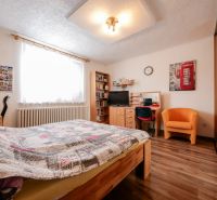 Priestranný 4 izbový rodinný dom po rekonštrukcii - Branč  - Spálňa v rodinnom dome s podlahou s dreveným dekorom, posteľou a pracovným stolom.