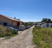 Základová doska na  575 m2 pozemku - Čeľadice  - Čeľadice: Pozemky - bývanie s domami, cestou a parkovanými autami uprostred prírody.