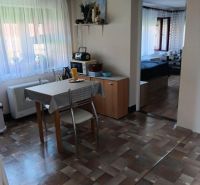 Slnečný pozemok s rodinným domom v Ovčiarsku  - Jedáleň s presklenými oknami, stolom, stoličkami a podlahou s dreveným dekorom.