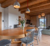 I Luxusné dvojpodlažné chalet pri Liptovskej Mare - Svetlý interiér s drevenými trámami, podlahou s dreveným dekorom a jedálenským stolom. Hotely a penzióny.