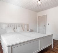 Stavebný pozemok 8 500 m² s podnikateľským potenciálom - Biela spálňa s manželskou posteľou a podlahou s dreveným dekorom.