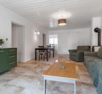 Stavebný pozemok 8 500 m² s podnikateľským potenciálom - Obývacia izba s pohovkou, krbom, jedálenským stolom a podlahou s dreveným dekorom.