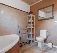 Stavebný pozemok 8 500 m² s podnikateľským potenciálom - Kúpeľňa s vaňou, toaletou, policami a zrkadlom, podlaha s dreveným dekorom.
