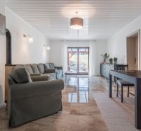 Stavebný pozemok 8 500 m² s podnikateľským potenciálom - Interiér obývacej izby s veľkou sedacou súpravou, jedálenským stolom a výhľadom do záhrady.