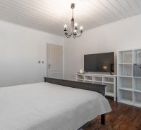 Stavebný pozemok 8 500 m² s podnikateľským potenciálom - Spálňa s lusterom, TV, regálmi a podlahou s dreveným dekorom. Pozemky - bývanie.