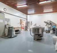I PREDAJ – FUNGUJÚCA PEKÁREŇ A POTRAVINY V TRNAVE - Výrobné priestory s nerezovými zariadeniami, bielymi dlaždicami a podlahou v priemyselnom štýle.