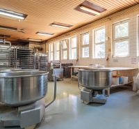 I PREDAJ – FUNGUJÚCA PEKÁREŇ A POTRAVINY V TRNAVE - Výrobné priestory s veľkými kovovými nádobami, regálmi a svietidlami, podlaha s dreveným dekorom.