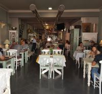ZNÍŽENÁ CENA! I Predaj komerčného priestoru na ul. Obchodna - Interiér obchodných priestorov s návštevníkmi pri stoloch a dekoráciami v retro štýle.