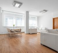I Predaj priestranného 3-i bytu pri Klientskom centre - Obývacia izba v 3-izbovom byte s podlahou s dreveným dekorom a bielym nábytkom.