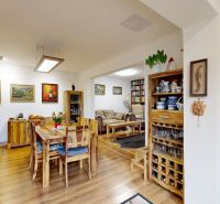 Rodinný dom 240 m², 3 bytové jednotky, veľký pozemok, Lamač - Obývacia izba rodinného domu s krbom, podlahou s dreveným dekorom a umeleckými obrazmi.