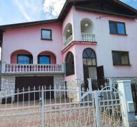 Veľký dom s veľkou garážou v Mankovciach  - Rodinný dom v Mankovciach s ružovou fasádou, poschodím a kovaným plotom.