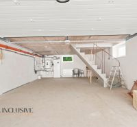 MODERNÁ NOVOSTAVBA | NITRA | MLYNÁRCE | POĽNÁ - Garáž v rodinnom dome s betónovou podlahou a schodmi, jednoduché biele steny.