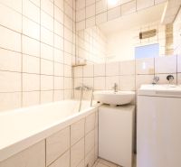 Čiastočne zrekonštruovaný 3 izbový byt s loggiou  - Kúpeľňa v 3-izbovom byte so svetlými obkladmi, práčkou a vaňou.