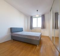 Čiastočne zrekonštruovaný 3 izbový byt s loggiou  - Spálňa v 3-izbovom byte s posteľou a zrkadlovou skriňou, podlaha s dreveným dekorom.