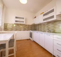 Čiastočne zrekonštruovaný 3 izbový byt s loggiou  - Kuchyňa v 3-izbovom byte s podlahou s dreveným dekorom a bielym nábytkom.