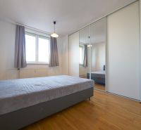 Čiastočne zrekonštruovaný 3 izbový byt s loggiou  - Spálňa v 3-izbovom byte s veľkou skriňou a podlahou s dreveným dekorom.
