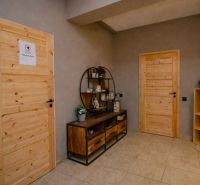 I Dom s wellness, bazénom a hotovým biznis potenciálom - Chodba v rodinnom dome, drevený nábytok, zrkadlo a dve zamknuté dvere.