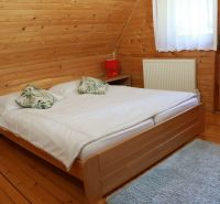 Chalupa Tále, okr.Brezno, pozemok 680m2,  - Spálňa v chate s dreveným obkladom, posteľou a podlahou s dreveným dekorom.