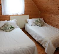 Chalupa Tále, okr.Brezno, pozemok 680m2,  - Spálňa chaty s dreveným obkladom, dvoma posteľami a dekoratívnymi vankúšmi.