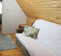 Chalupa Tále, okr.Brezno, pozemok 680m2,  - Pohodlný gauč s dekoračným vankúšom v útulnej chate s drevenými dekoráciami.