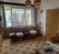 Slnečný 1-izbový byt  na predaj, 42 m2,  J. Gagarina, Zvolen - Izba v 1-izbovom byte so starožitným nábytkom, kobercom a záclonami na oknách.