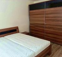 Prerobený 2 izbový byt v centre mesta Nové Zámky - Spálňa v 2-izbovom byte s posteľou a veľkou skriňou, podlaha s dreveným dekorom.