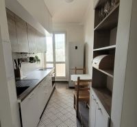PRENÁJOM - 3-izbový svetlý byt - Teplická ulica, Bratislava - Úzka kuchyňa s bielymi skrinkami a tmavou podlahou v 3-izbovom byte.