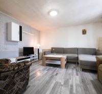 3 izbový Rodinný dom v Cabaj-Čápore s pozemkom 1 053 m² - Obývacia izba s kobercami, sedačkou, televíziou a podlahou s dreveným dekorom v rodinnom dome.