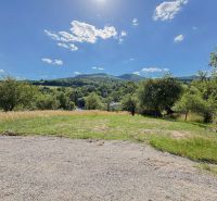 Ideálny Stavebný pozemok 1 353 m² pri Tajchu s krásnymi výhľadmi - Pozemky - bývanie v Novej Bani obkolesené prírodou, lúkami a stromami pod modrou oblohou.