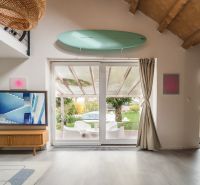 Dom medzi stromami: Nadčasová architektúra v Cabaj-Čápore - Obývačka v rodinnom dome s TV, podlaha s dreveným dekorom, výhľad na terasu.