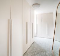Dom medzi stromami: Nadčasová architektúra v Cabaj-Čápore - Biela vstavaná skriňa so zrkadlom a vzorovanou podlahou v rodinnom dome.