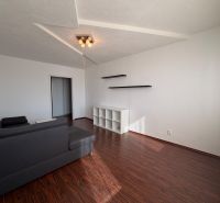 NOVINKA!!! Priestranný 3-izbový byt, 72 m² | Karpatská, Sásová - Obývačka v 3-izbovom byte s podlahou s dreveným dekorom, sivou sedačkou a poličkami.