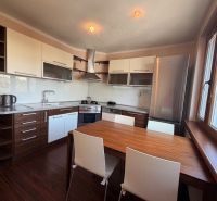 NOVINKA!!! Priestranný 3-izbový byt, 72 m² | Karpatská, Sásová - Kuchyňa s bielymi skrinkami, podlaha s dreveným dekorom a jedálenský stôl.