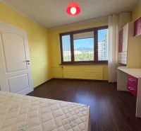 NOVINKA!!! Priestranný 3-izbový byt, 72 m² | Karpatská, Sásová - Žlté steny izby s podlahou s dreveným dekorom v 3-izbovom byte.