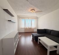 NOVINKA!!! Priestranný 3-izbový byt, 72 m² | Karpatská, Sásová - Obývačka v 3-izbovom byte s podlahou s dreveným dekorom a rohovou sedačkou.