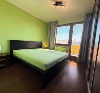 NOVINKA!!! Priestranný 3-izbový byt, 72 m² | Karpatská, Sásová - Spálňa v 3-izbovom byte s podlahou s dreveným dekorom a zelenými stenami.