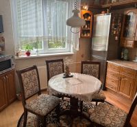 NA PREDAJ PRIESTRANNÝ 3-IZBOVÝ BYT | 67 m² | LODŽIA | 4. POSCHODIE - Kuchyňa v 3-izbovom byte s podlahou s dreveným dekorom a čipkovaným obrusom na stole.