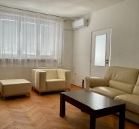 I PREDAJ 2-IZBOVÝ BYT S KLIMATIZÁCIOU A BALKÓNOM I RUŽINOV - Obývacia izba v 2-izbovom byte s krémovou sedačkou a podlahou s dreveným dekorom.
