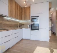Na predaj štýlový 2,5-izbový byt - Poprad Západ, novostavba URSUS - Kuchyňa v 3-izbovom byte s bielymi skrinkami a podlahou s dreveným dekorom.