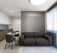 REZERVOVAÝ 3 izbový na predaj Tomčany, 136 m2 poschodie 3 terasa 59 m2 - Obývacia časť 3-izbového bytu s pohovkou a jedálenským stolom, podlaha s dreveným dekorom.