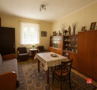NA PREDAJ - Rodinný dom - Banská Bystrica - CENTRUM - Obývacia izba s dreveným nábytkom, podlahou s dreveným dekorom, kobercom a dekoračnými predmetmi.
