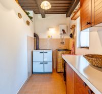 Rekreačná chata s krásnym pozemkom a potenciálom výstavby domu - Kuchynka v chate s bielymi stenami, hnedými skrinkami a spotrebičmi.