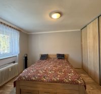 Na predaj 3 byt Žiar nad Hronom, 75m2 - Spálňa v 3-izbovom byte s posteľou, vstavanou skriňou a podlahou s dreveným dekorom.