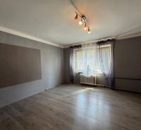 Na predaj 3 byt Žiar nad Hronom, 75m2 - Obývacia izba v 3-izbovom byte s podlahou s dreveným dekorom a veľkým oknom.