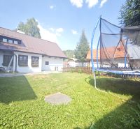 Predaj: Štýlová chalupa v srdci Španej Doliny miesto s atmosférou  - Chata v Španej Doline s trampolínou na trávnatej záhrade pod modrou oblohou.
