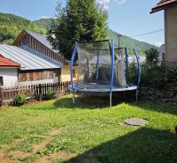 Predaj: Štýlová chalupa v srdci Španej Doliny miesto s atmosférou  - Trampolína pri chate v Španej Doline, obklopená trávou a stromami v pozadí.