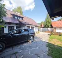 Predaj: Štýlová chalupa v srdci Španej Doliny miesto s atmosférou  - Auto zaparkované pri chate v Španej Doline, s viditeľnými strechami a plotom.