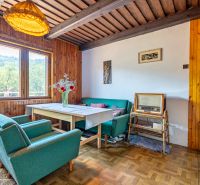 Rekreačná chata s krásnym pozemkom a potenciálom výstavby domu - Interiér chaty s retro nábytkom a podlahou s dreveným dekorom, pohodlné kreslá, vintage rádio.