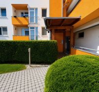 Krásny priestranný klimatizovaný 1izbový byt s terasou 66m2 - Farebná fasáda budovy obklopená zelenými kríkmi na Čerešňovej ulici v Chorvátskom Grobe.